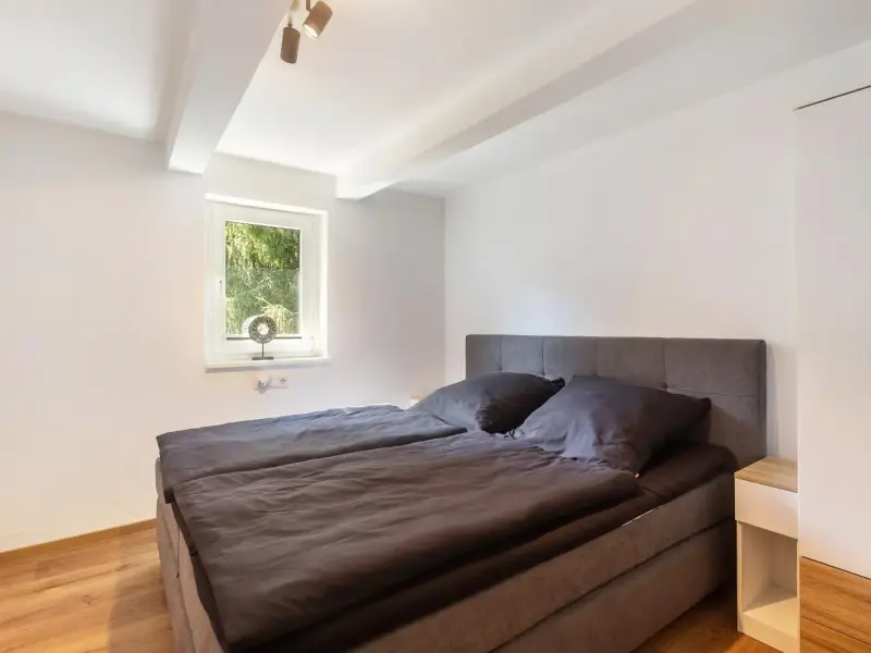Schlafzimmer mit Boxspringbett und grossem Fenster, Deluxe Apartment