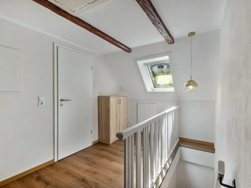 Treppenaufgang mit freiliegendem Holzbalken und Dachfenster zum Superior Apartment